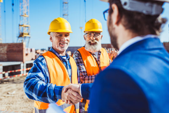 A construction site manager meeting an insurance provider visiting for an inspection